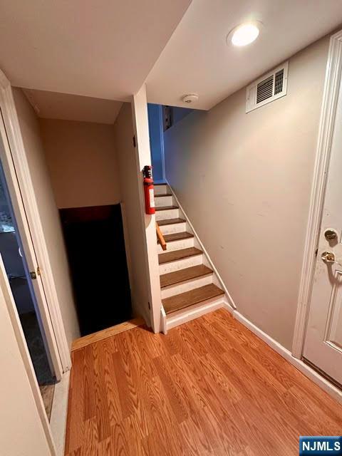 staircase with wood finished floors and visible vents