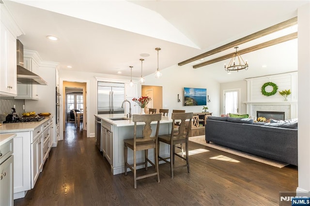 kitchen featuring vaulted ceiling with beams, a breakfast bar, light countertops, stainless steel appliances, and a sink