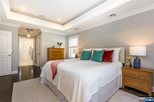 bedroom featuring visible vents, crown molding, a raised ceiling, and wood finished floors