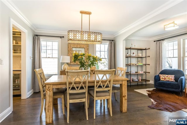 dining room with arched walkways, dark wood-type flooring, and ornamental molding