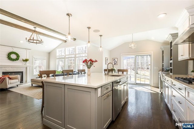 kitchen featuring a kitchen bar, lofted ceiling, a glass covered fireplace, stainless steel appliances, and a sink