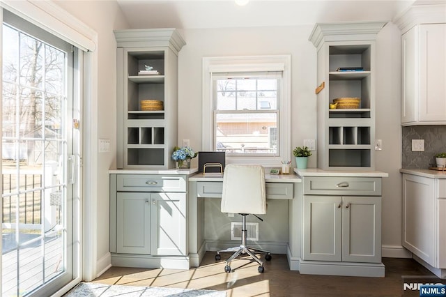 office featuring a wealth of natural light, dark wood-style flooring, and built in desk