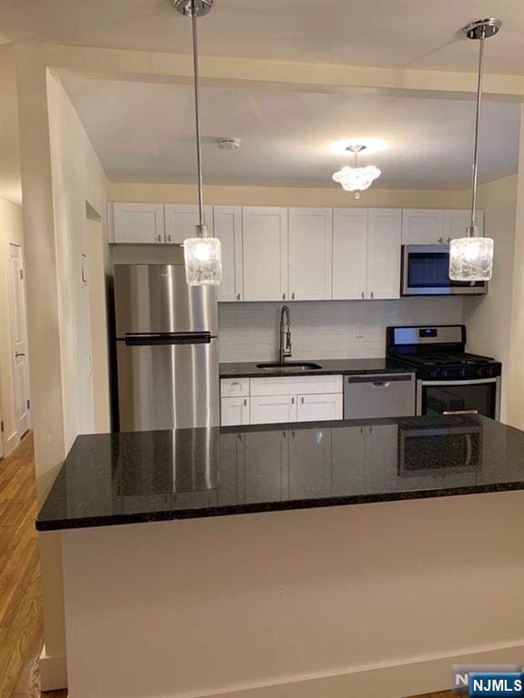 kitchen featuring a center island, light wood-style flooring, stainless steel appliances, white cabinetry, and a sink