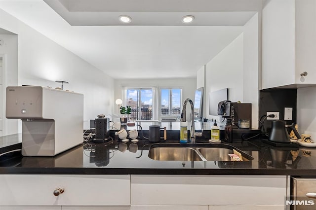 kitchen with white cabinetry, dark countertops, recessed lighting, and a sink