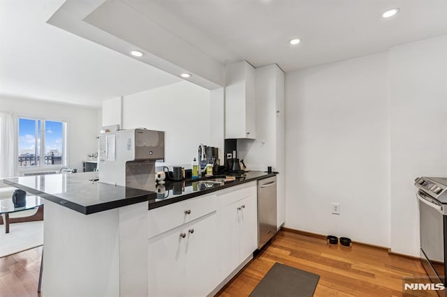 kitchen with light wood-type flooring, dark countertops, dishwasher, and white cabinets