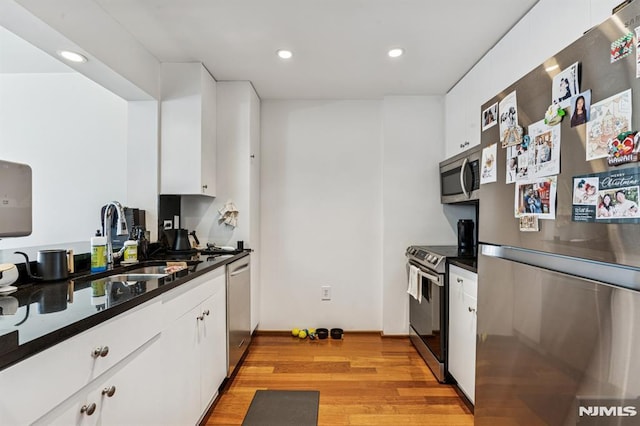 kitchen with a sink, dark countertops, white cabinets, and stainless steel appliances