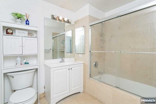 full bath featuring tile patterned floors, combined bath / shower with glass door, toilet, and vanity