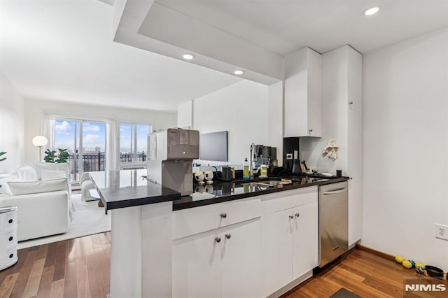 kitchen with open floor plan, dark countertops, dishwasher, and wood finished floors