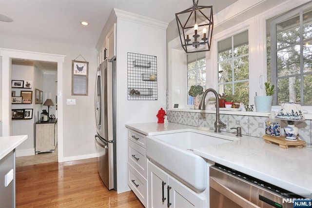 kitchen featuring a sink, appliances with stainless steel finishes, white cabinets, and light countertops