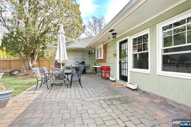 view of patio with area for grilling, outdoor dining area, and fence