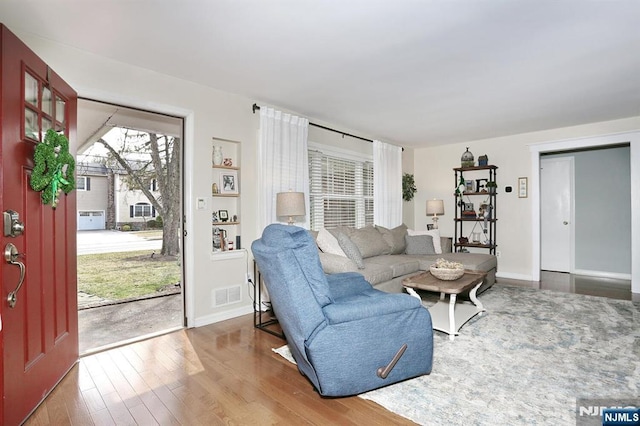 living room with wood finished floors, visible vents, and baseboards