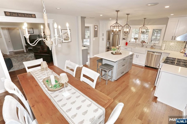 dining area featuring recessed lighting, light wood-type flooring, and an inviting chandelier