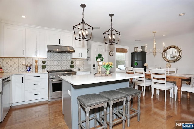 kitchen with light wood-style flooring, stainless steel appliances, light countertops, white cabinets, and under cabinet range hood