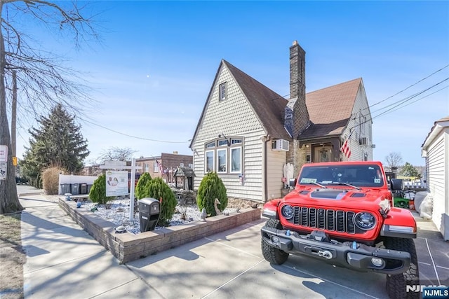 view of front of home featuring an AC wall unit, a chimney, and roof with shingles