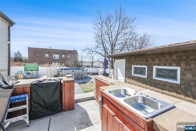 view of patio / terrace with a sink, a hot tub, and fence