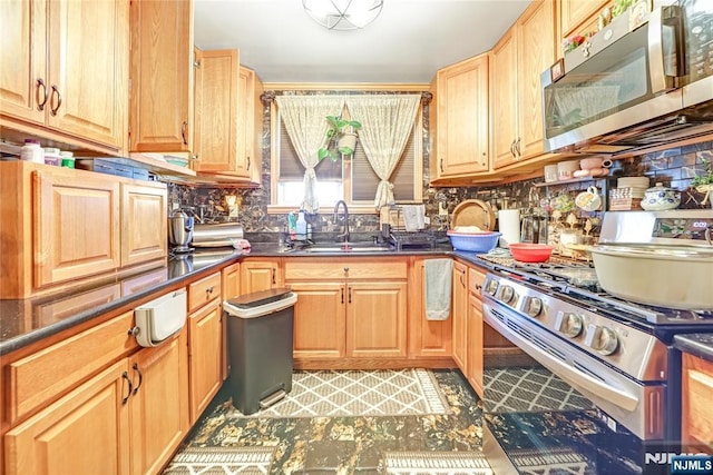 kitchen with a sink, dark countertops, backsplash, and stainless steel appliances