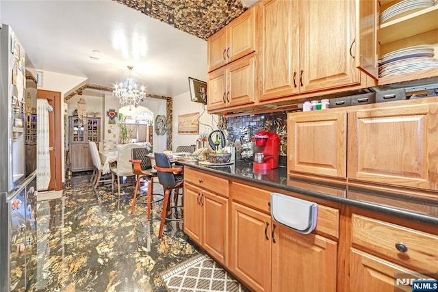 kitchen with dark countertops, a chandelier, and tasteful backsplash