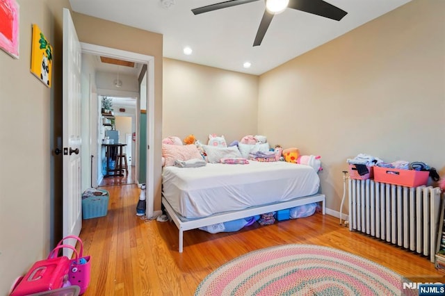 bedroom featuring wood finished floors, recessed lighting, radiator, baseboards, and attic access