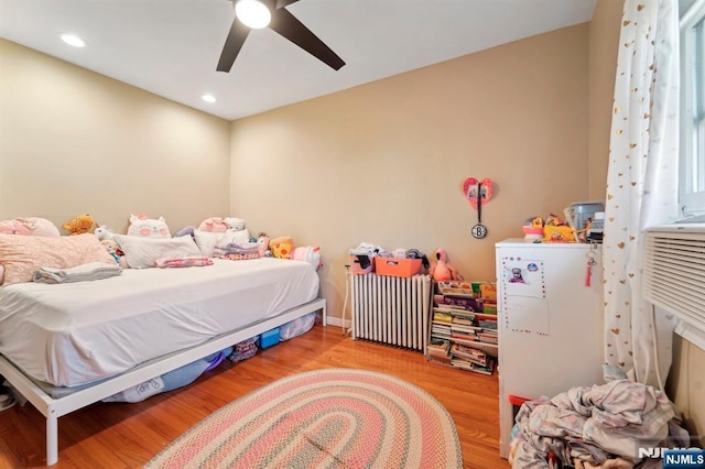 bedroom featuring radiator, wood finished floors, baseboards, recessed lighting, and ceiling fan