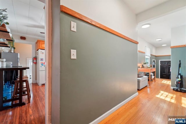 hallway featuring light wood-style floors and baseboards