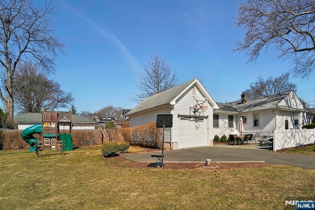 exterior space with driveway, a playground, a garage, and fence