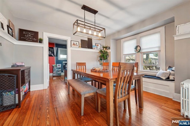 dining space featuring radiator heating unit, baseboards, and wood-type flooring