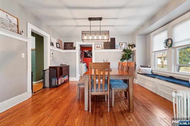 dining area featuring baseboards, wood-type flooring, and radiator