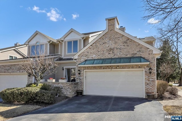 view of front of property featuring a chimney, driveway, and an attached garage