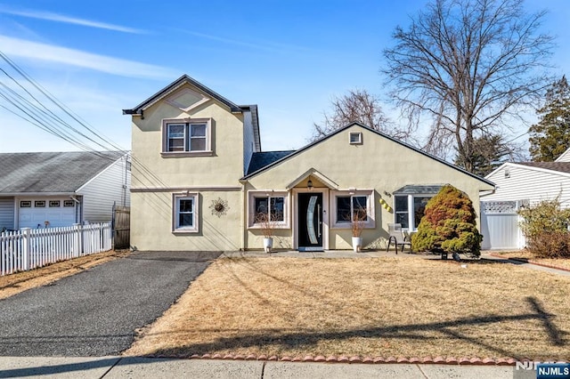 traditional home with stucco siding, driveway, and fence