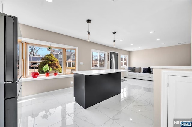 kitchen with light countertops, recessed lighting, marble finish floor, and freestanding refrigerator