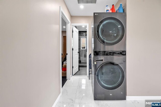 clothes washing area with visible vents, marble finish floor, stacked washer and clothes dryer, baseboards, and laundry area