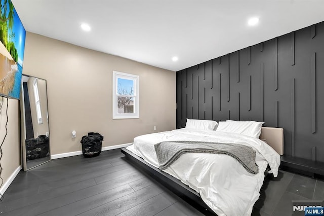 bedroom featuring recessed lighting, dark wood-type flooring, baseboards, and an accent wall