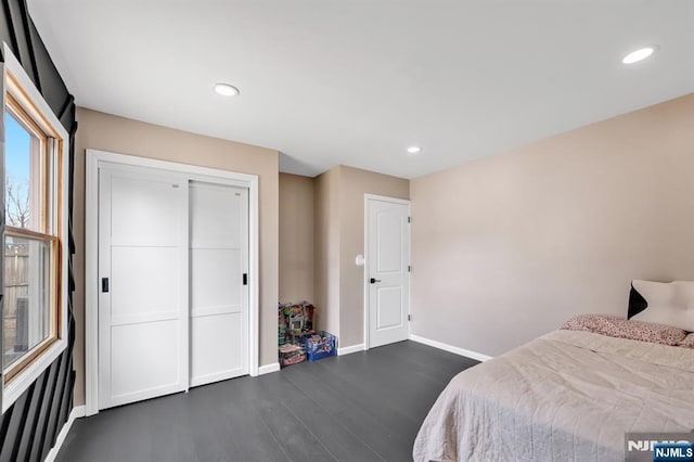 bedroom with dark wood finished floors, recessed lighting, a closet, and baseboards