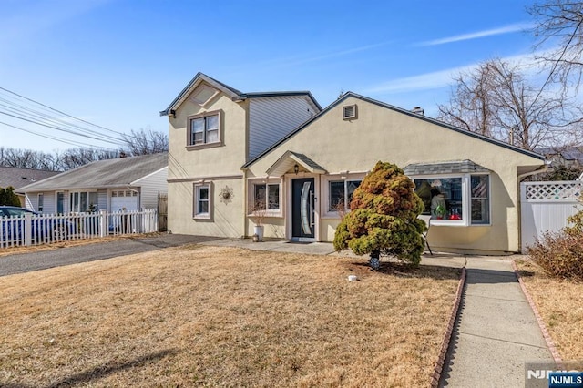 traditional-style home featuring stucco siding, a front yard, and fence