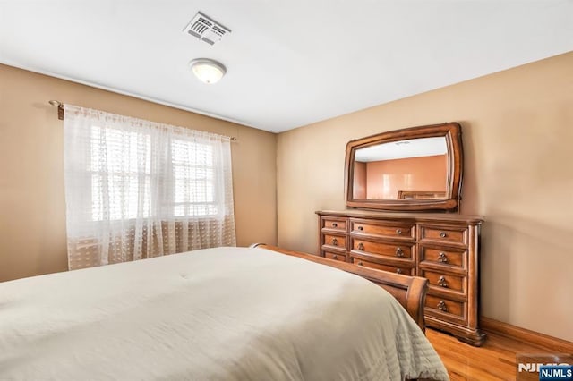 bedroom featuring visible vents, baseboards, and wood finished floors