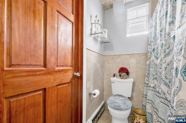 bathroom featuring a baseboard heating unit, a wainscoted wall, toilet, tile patterned floors, and tile walls