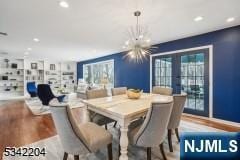 dining room featuring french doors, a notable chandelier, a healthy amount of sunlight, and wood finished floors