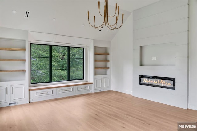 16 Donnybrook Dr, Demarest, NJ 07627 - unfurnished living room with light wood-type flooring, a chandelier, built in features, a glass covered fireplace, and lofted ceiling