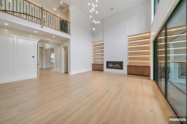 16 Donnybrook Dr, Demarest, NJ 07627 - unfurnished living room with a high ceiling, wood finished floors, a glass covered fireplace, baseboards, and crown molding