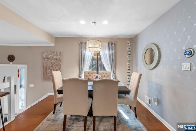 dining area featuring visible vents, wallpapered walls, an accent wall, baseboards, and wood finished floors