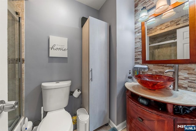 bathroom with decorative backsplash, toilet, vanity, and a shower with door