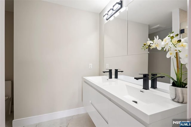 bathroom featuring a sink, visible vents, baseboards, and double vanity