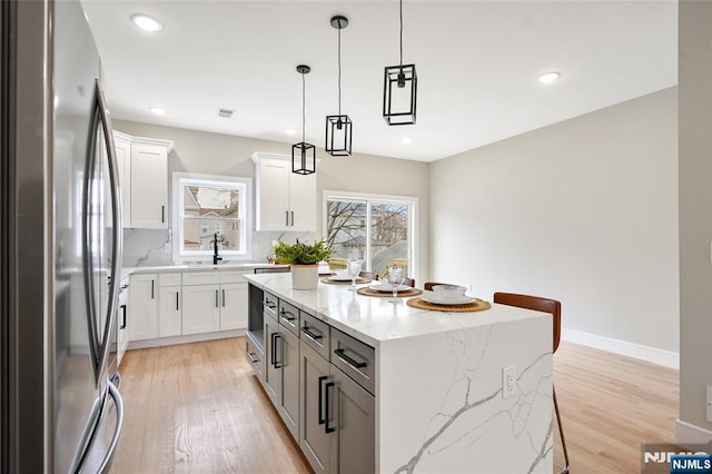 kitchen featuring decorative backsplash, light wood-style flooring, a center island, and freestanding refrigerator