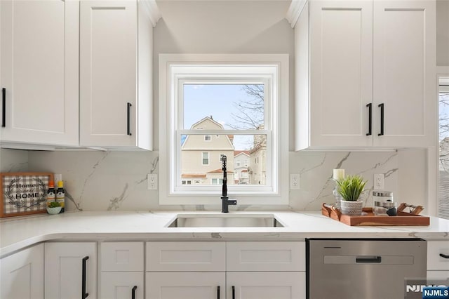 kitchen with backsplash, a sink, white cabinets, and stainless steel dishwasher