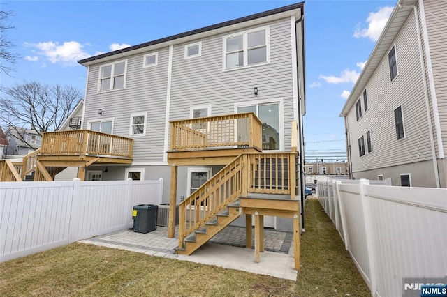 back of property with a lawn, a deck, a fenced backyard, stairway, and a patio area