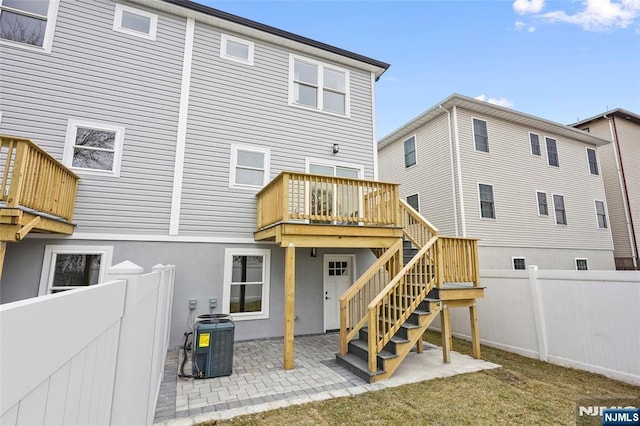 rear view of property with cooling unit, a patio, a fenced backyard, and stairway