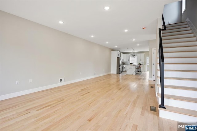 unfurnished living room featuring visible vents, recessed lighting, stairs, and light wood-style floors