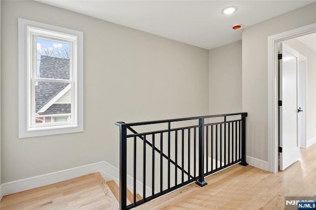 corridor featuring wood finished floors, recessed lighting, an upstairs landing, and baseboards