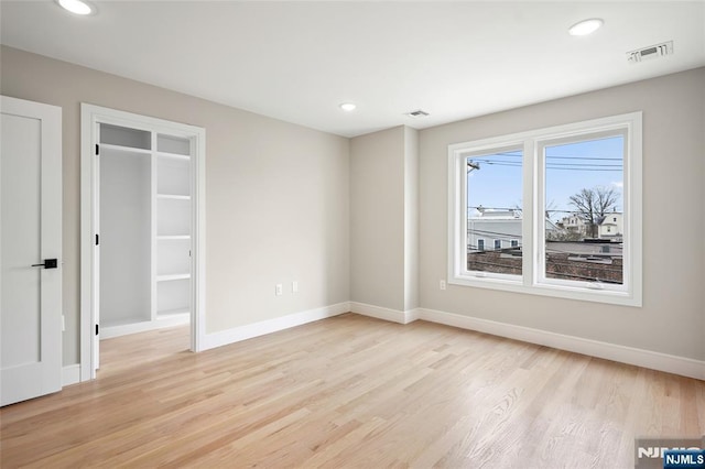 unfurnished bedroom featuring light wood finished floors, visible vents, and baseboards