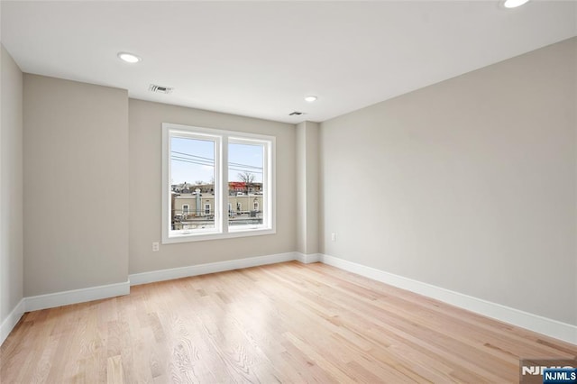 spare room with light wood-type flooring, visible vents, baseboards, and recessed lighting